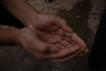 
water falling on the palms of a young person