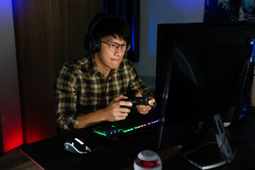 Asian man cyber sport gamer concentrated playing video games on computer eSport concept © snowing12