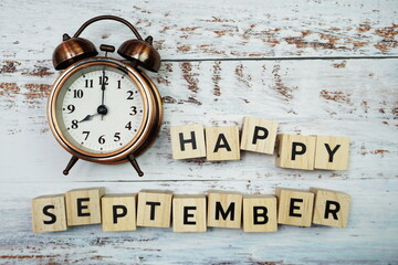Happy September alphabet letters with alarm clock on wooden background