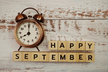 Happy September with alarm clock on wooden background