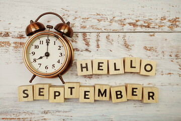 Hello September with alarm clock on wooden background