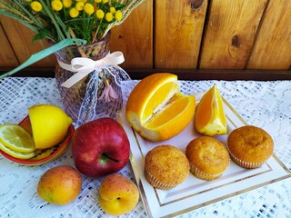 Obraz na płótnie Canvas Food still life on the kitchen table a vase of wild flowers apples apricots sponge cakes lemon orange cookies in a basket