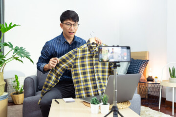 Asian blogger recording vlog video on camera review of product at home office