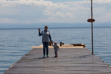 Grandmother and granddaughter walk on the pier on the lake