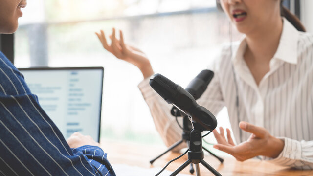 Asian women podcaster podcasting and recording online talk show at studio using headphones