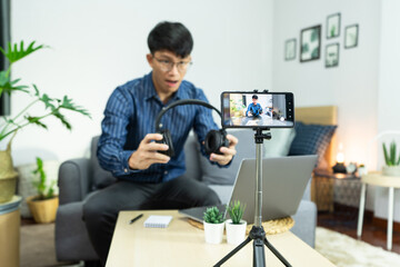 Asian blogger recording vlog video on camera review of product at home office