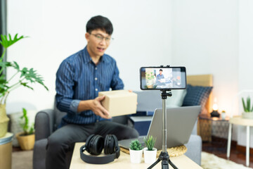 Asian blogger recording vlog video on camera review of product at home office