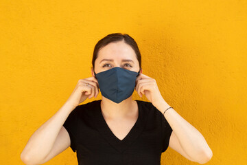 Woman wearing a blue facemask, front shoot, outdoors with bright yellow background