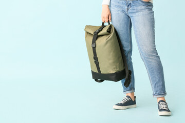Young woman with backpack on color background