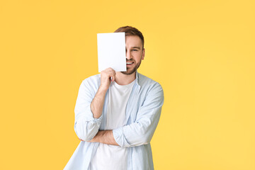 Young man with blank card on color background