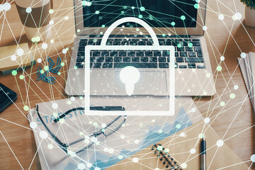 Double exposure of desktop with computer and lock icon hologram. Concept of data safety.