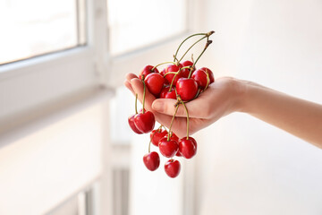 Woman with sweet cherry at home, closeup