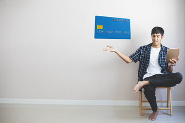 Fototapeta premium Man working on sofa in home hold smartphone with credit card for dollar shopping online.you enjoy happy freedom happiness lifestyle new normal travel During epidemic coronavirus covid-19.