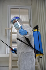 A man in protection germ suit or PPE suit with Equipment Face shield, Mask, and Alcohol gel for cleaning place and fighting Corona virus (covid 19) outbreak quarantine/disinfection
