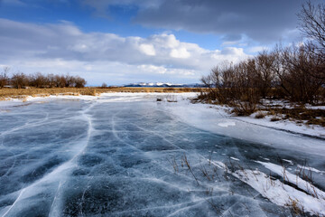 Frozen river with beautiful stratus clouds over the ice surface on a frosty day.