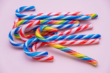 lot of multi-colored candy canes on a pink background, copy space