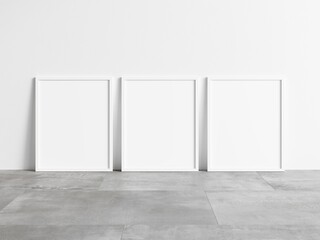 Three vertical empty white frame mock up on concrete floor. Blank frame mockup. 3d illustrations.