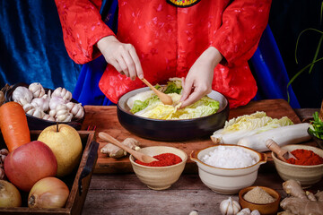 Korean women wearing traditional red hanboks doing kimchi She is mixing the ingredients in the bowl. To taste delicious. The concept of charming fermented cooking And fragrant, Asian food
