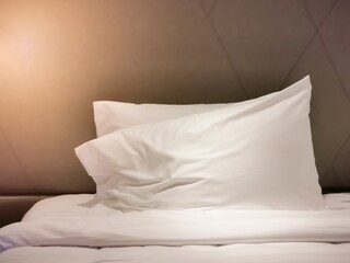 Luxury leather bedhead and white pillows with warm light.