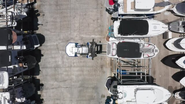 Over head view on loader carefully lifting the yacht at the multi-level boat parking. Beautiful slow motion drone video for yacht business. 4K aerial video of water transportation, Miami port, Florida