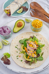 Fresh tortilla wraps with chicken, mushrooms and fresh vegetables on wooden board