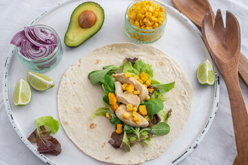 Fresh tortilla wraps with chicken, mushrooms and fresh vegetables on wooden board