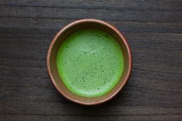 木のテーブルの上の泡だてた抹茶