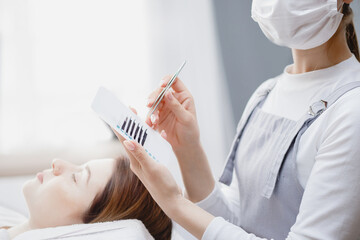 Master making fake long lash Eyelash extension procedure with tweezers for woman