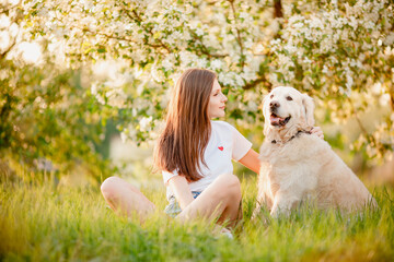 Best friends, young woman with dog retriever on walk in summer park, sun light