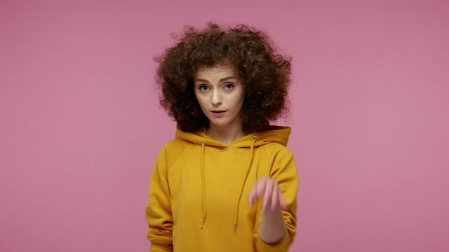 I'm ok! Pretty positive girl afro hairstyle in hoodie showing okay hand sign and winking as if approving suggestion, completely agree and support. indoor studio shot isolated on pink background