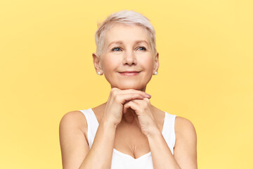 Portrait of attractive joyful middle aged woman with short stylish haircut and tanned skin placing...