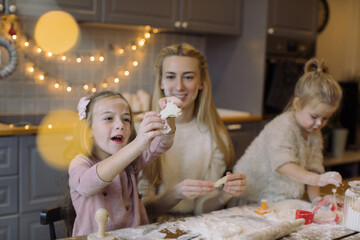 Happy family in the kitchen. Mother and two little daughters preparing the dough for Christmas cookies. Family winter holidays concept.