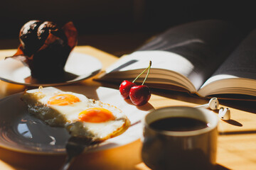 breakfast on the table coffee fried eggs and ripe cherries in the sunlight