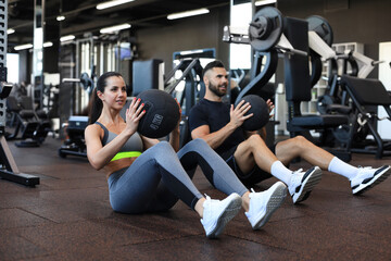 Fototapeta na wymiar Beautiful young sports couple is working out with medicine ball in gym.