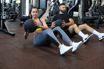 Fototapeta na wymiar Beautiful young sports couple is working out with medicine ball in gym.