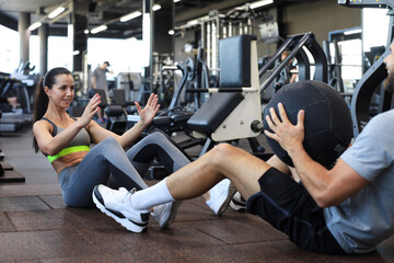 Fototapeta na wymiar Fit and muscular couple exercising with medicine ball at gym.