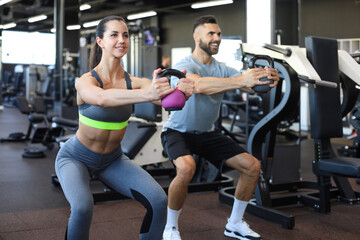 Fototapeta na wymiar Fit and muscular couple focused on lifting a dumbbell during an exercise class in a gym.