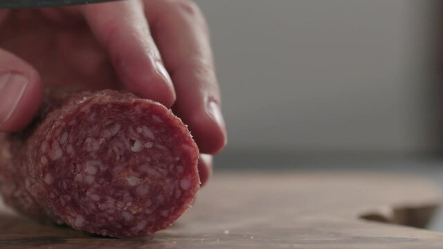 Slow motion slicing italian salame on wood board with copy space
