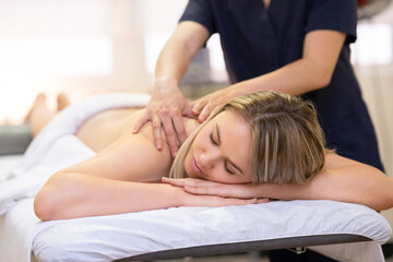 Obraz na płótnie Canvas Woman lying on a stretcher receiving a back massage.