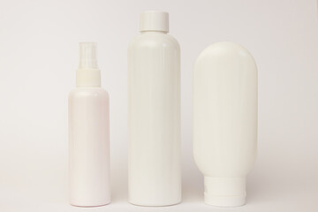 white plastic cosmetic jars and white open cream on a white background