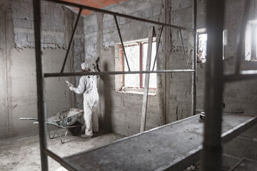 Real construction worker making a wall inside the new house.
