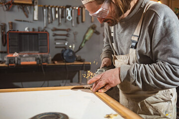 Male carpenter working on old wood in a retro vintage workshop.