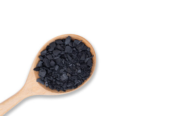 Natural broken black activated charcoal granular and powder in wooden spoon isolated on white...