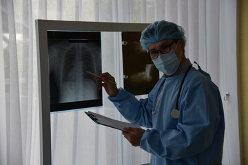 Asian male doctor is watching image of  X-ray film viewer of Patient for a physical examination...