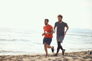 two guys running along the beach coast