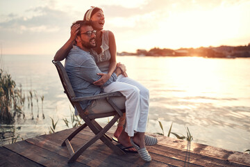 woman sitting in a lap of a man at sunset, laughing
