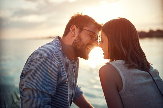 young adult couple is about to kiss by the sea at sunset
