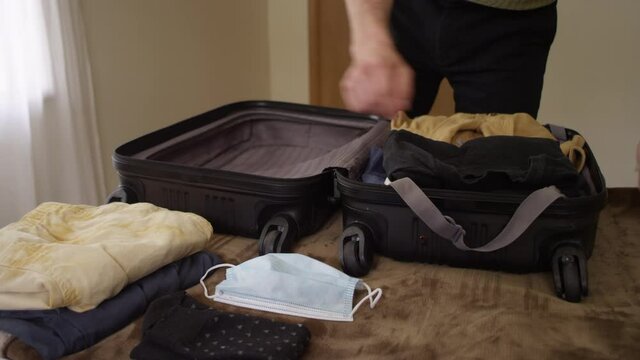 Man Neatly Packs A Suitcase With Clothes And Leaves Without Forgetting His Face Mask