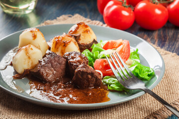 Pork meat stew served with potatoes and vegetable salad
