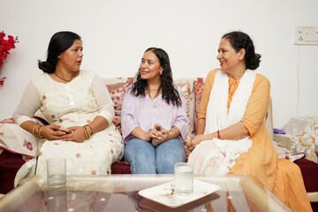 Two mid aged indian woman with a teen girl looking having a conversation.